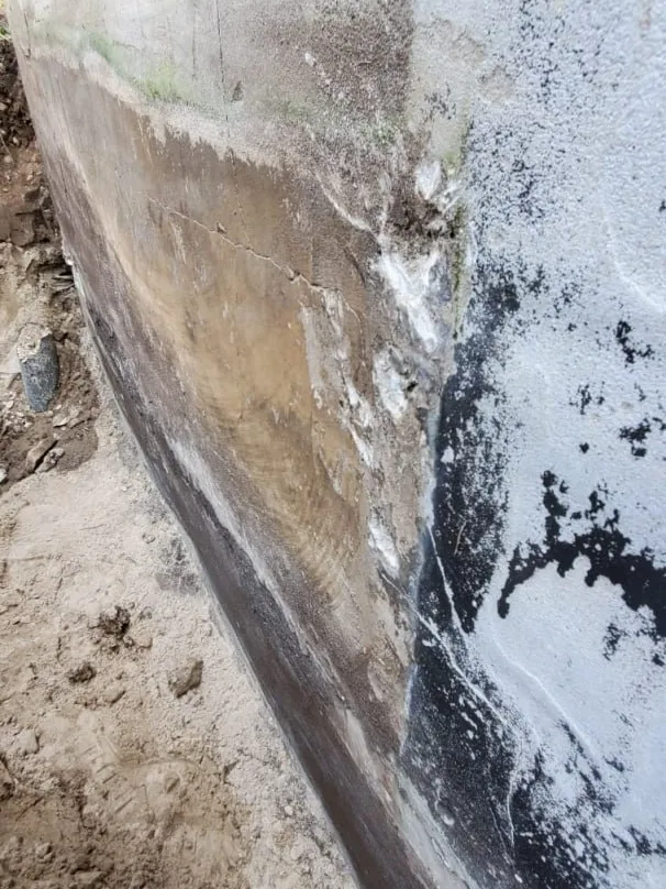Detailed waterproofing membrane installation on foundation wall