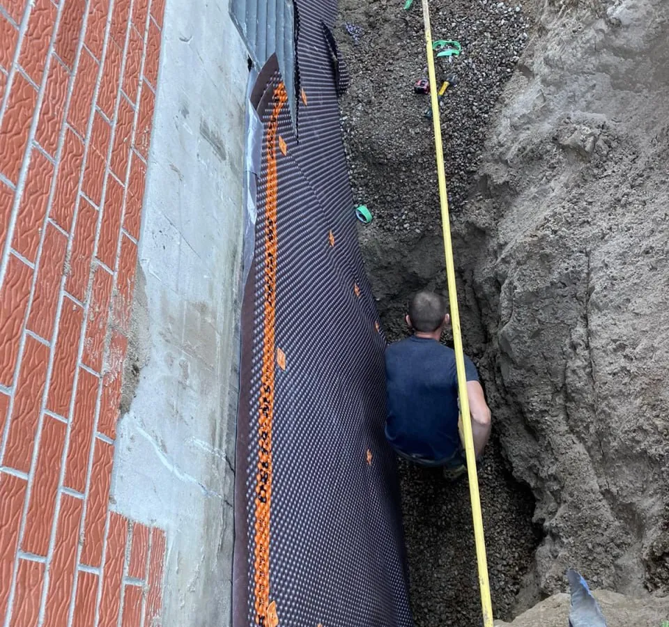 Completed exterior waterproofing on multi-unit building foundation